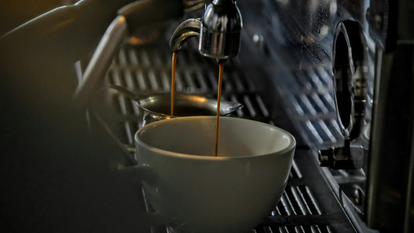 Espresso running from a machine into a white porcelain cup